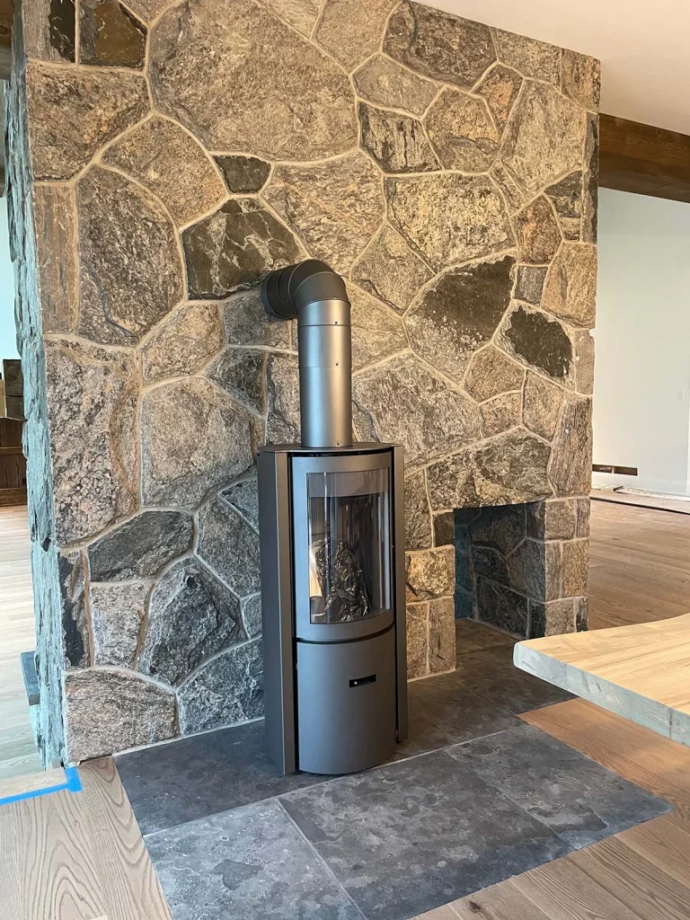 A cozy Stuv 30 recently installed into its new home with a rustic stone backdrop.